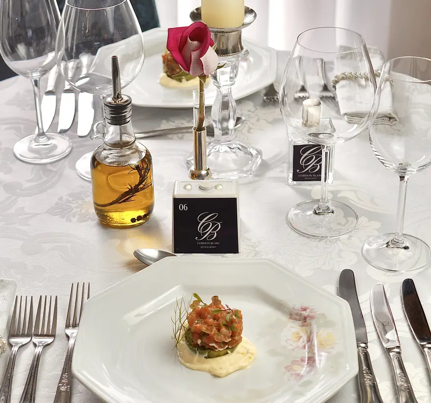 Mesa posta do Cordon Blanc com couvert servido, taças de cristal e vela acesa